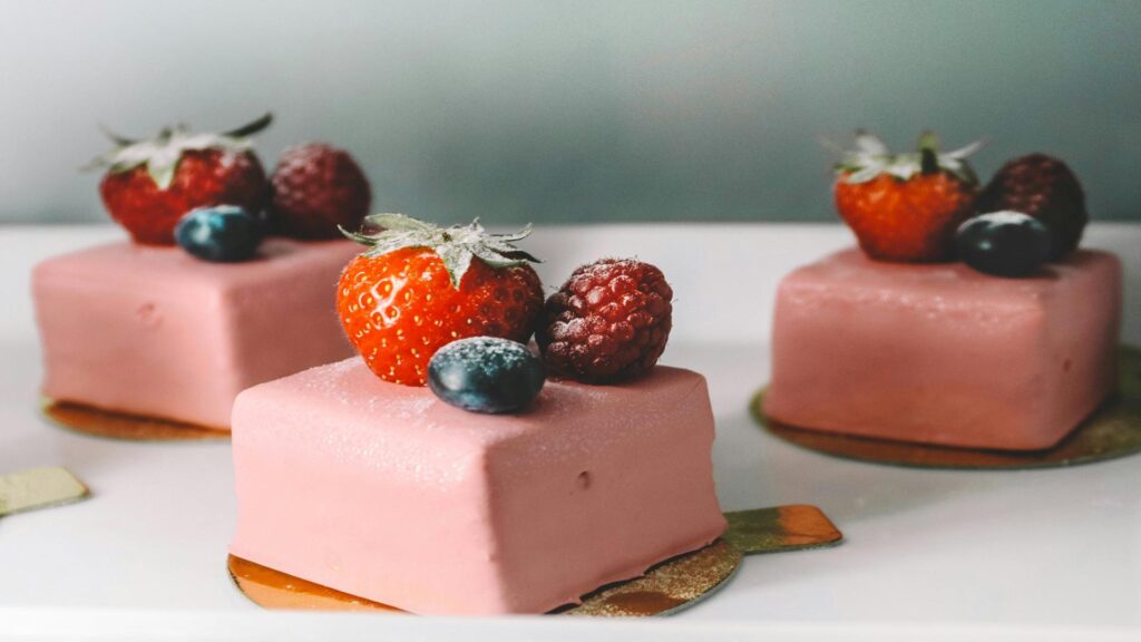 Pink square dessert topped with fresh strawberries, raspberries, and blueberries.