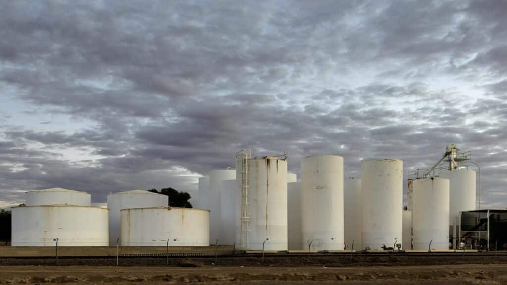 Large white industrial tanks under a cloudy sky