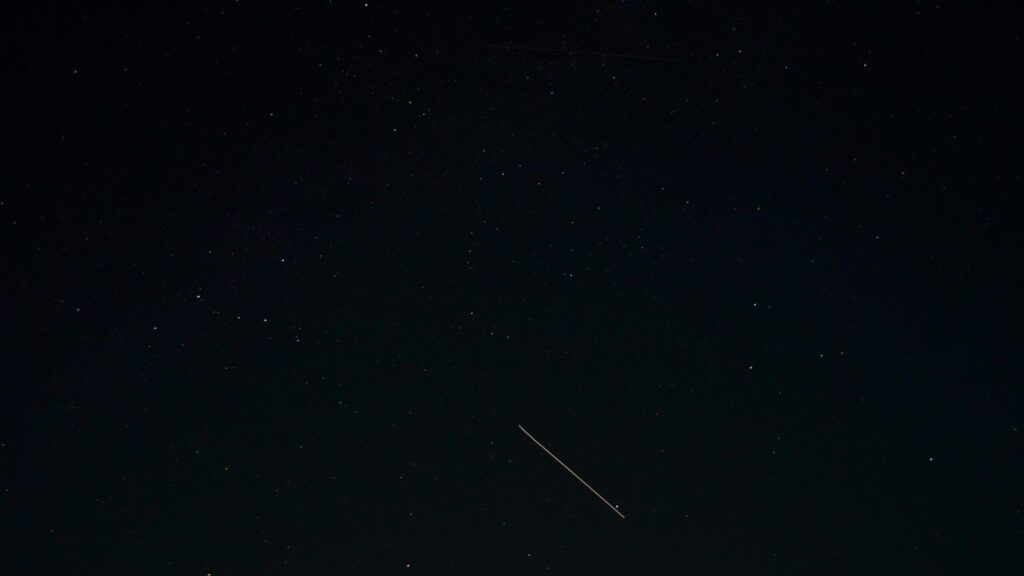 A dark night sky with a visible meteor trail