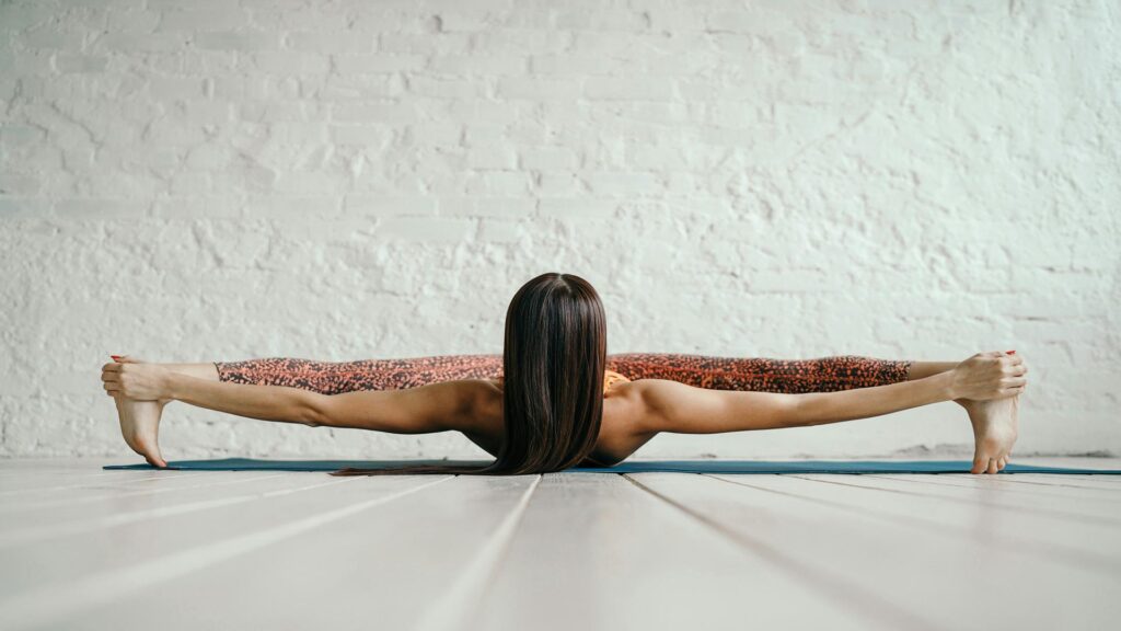 Person performing a yoga pose with legs stretched wide apart