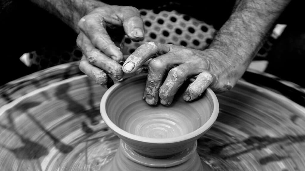 Hands shaping clay on a pottery wheel