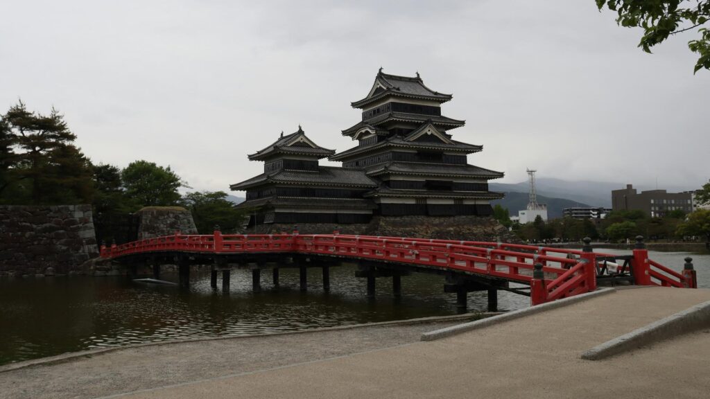 Matsumoto Castle with a red bridge over a moat on a cloudy day