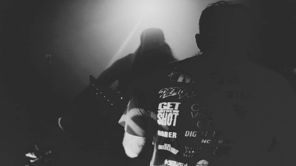 Black and white image of musicians silhouetted against bright concert lighting.