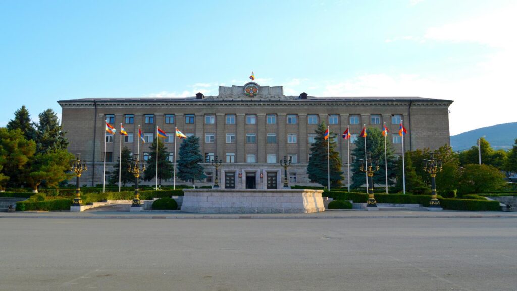 A government building with multiple flags displayed in front.