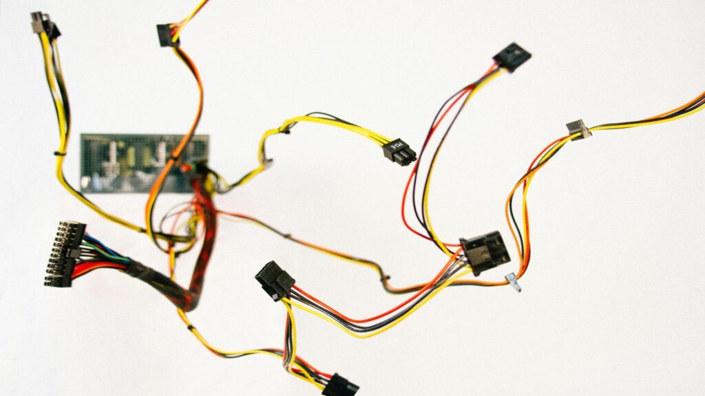 Close-up of electrical wiring harness with multiple colored cables and connectors against white background