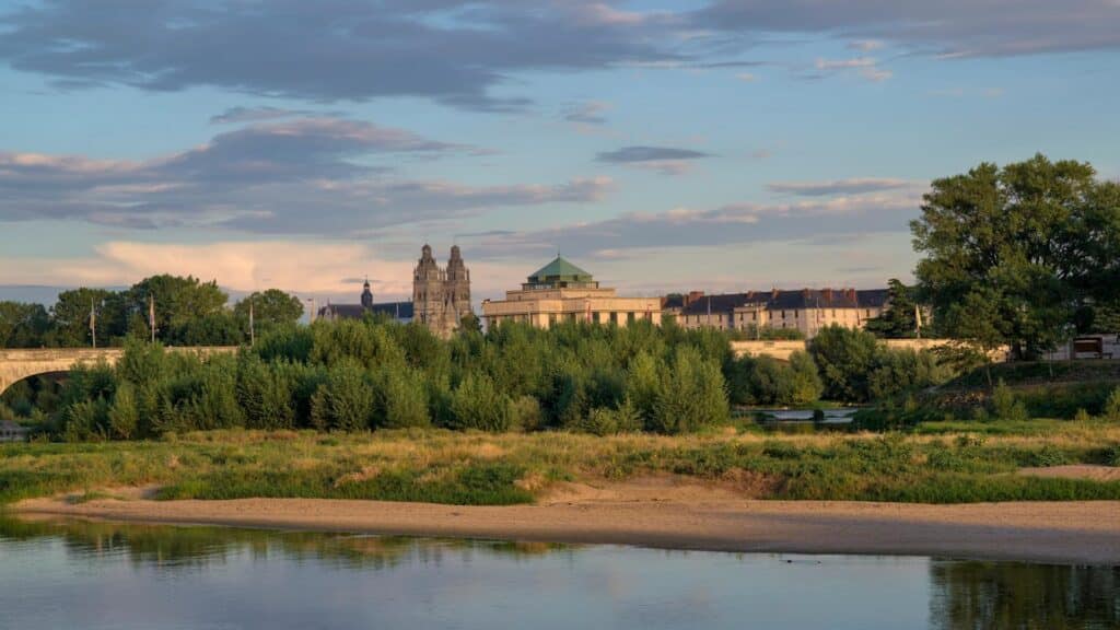 Scenic view of Tours city skyline with Saint Gatien Cathedral towers and Loire River in foreground during sunset