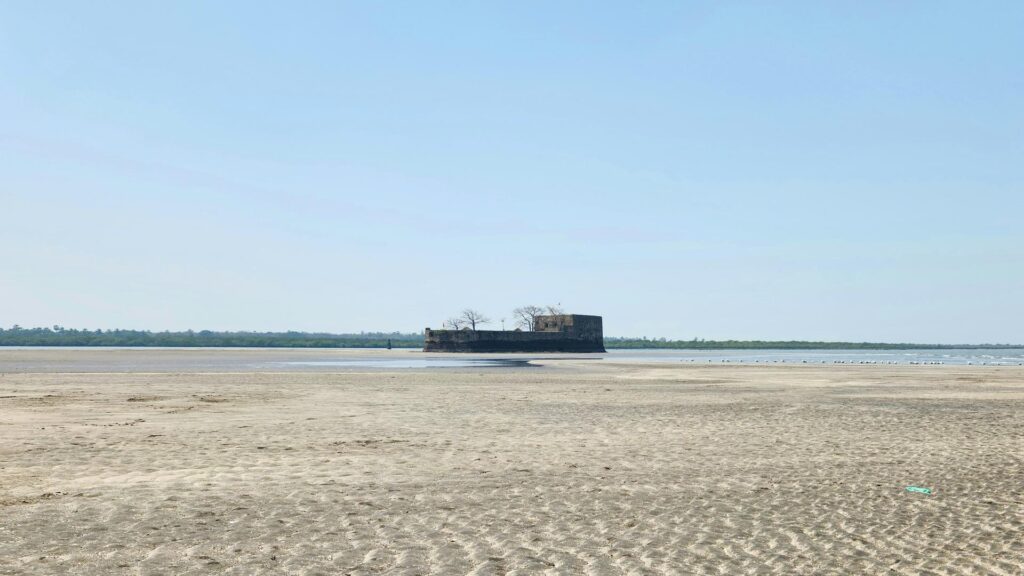 A solitary fort surrounded by sand and water under a clear blue sky.