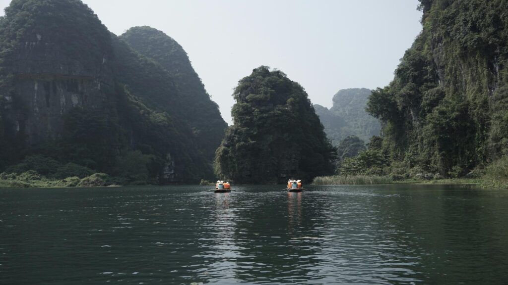 Boats navigating through lush green cliffs