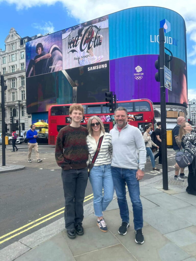 Family enjoying a Day Tour of London with iconic landmarks and a red double-decker bus in the background.