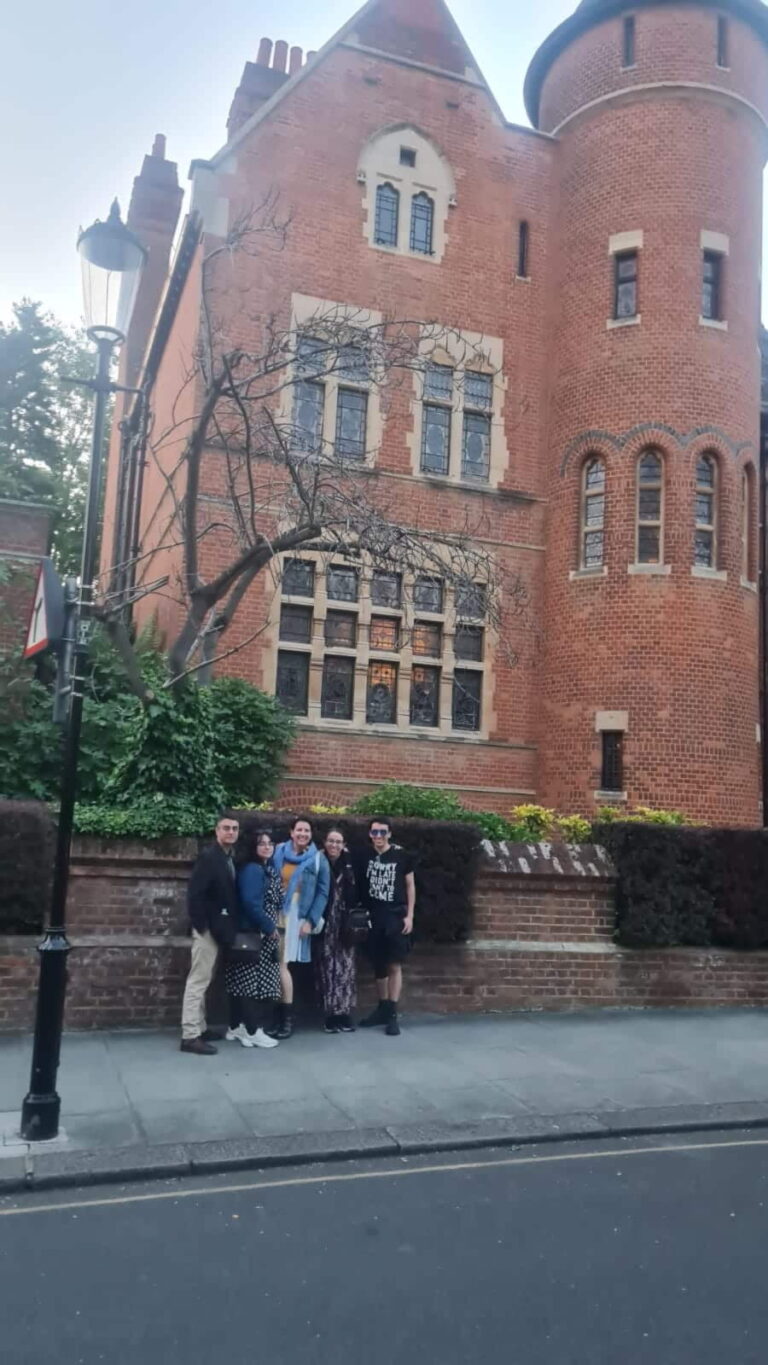 Top 10 Must Do In London - Group of tourists posing in front of a Victorian Gothic red brick building during London sightseeing taxi tour