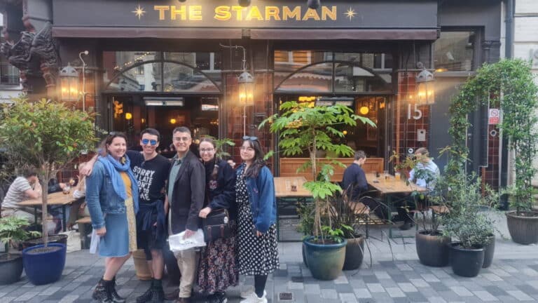 Group of people enjoying London sightseeing in front of The Starman pub, a notable stop during a London taxi tour.