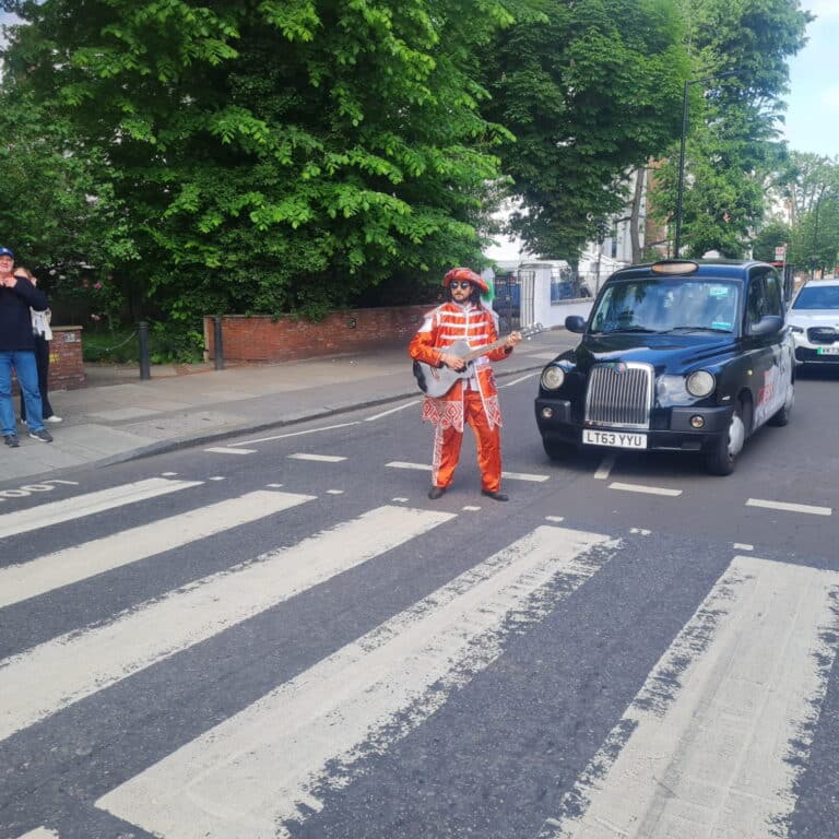 Tourist enjoying London Sightseeing Tickets experience with a musician on Abbey Road