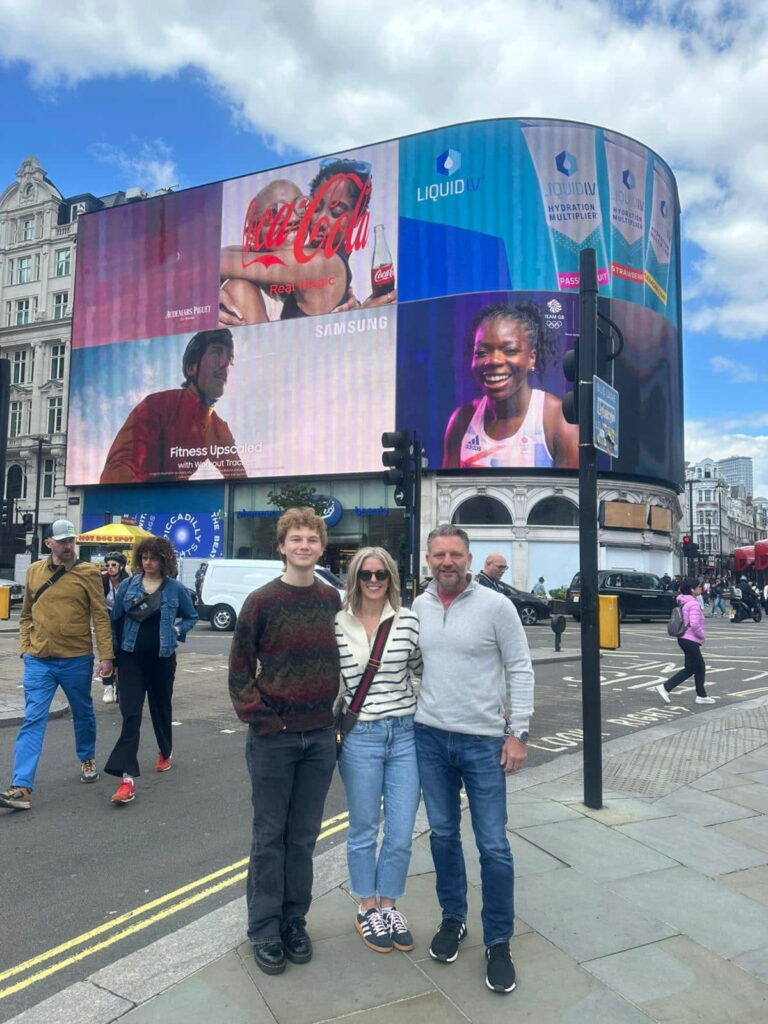 Group of tourists enjoying a sightseeing tour in London with iconic landmarks and advertisements in the background