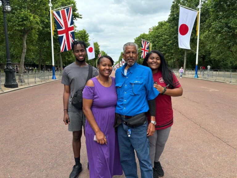 A family enjoying a day in London with London Sightseeing Taxi Tours, standing on a street adorned with British and Japanese flags.
