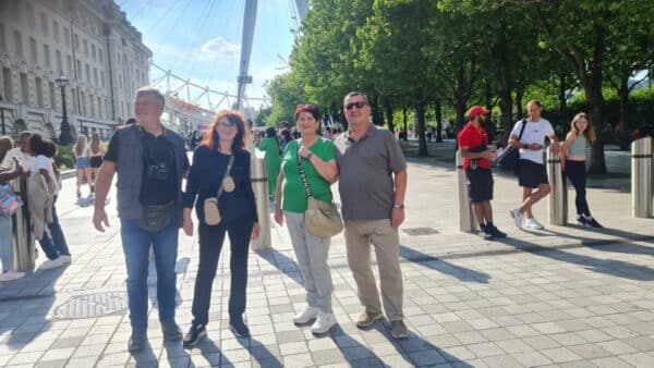 Group of tourists enjoying a guided trip to London with London Sightseeing Taxi Tours near the London Eye.