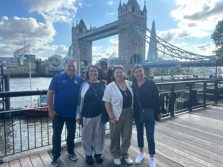 Group of people posing in front of Tower Bridge, a landmark in London, showcasing Beautiful Places Of London