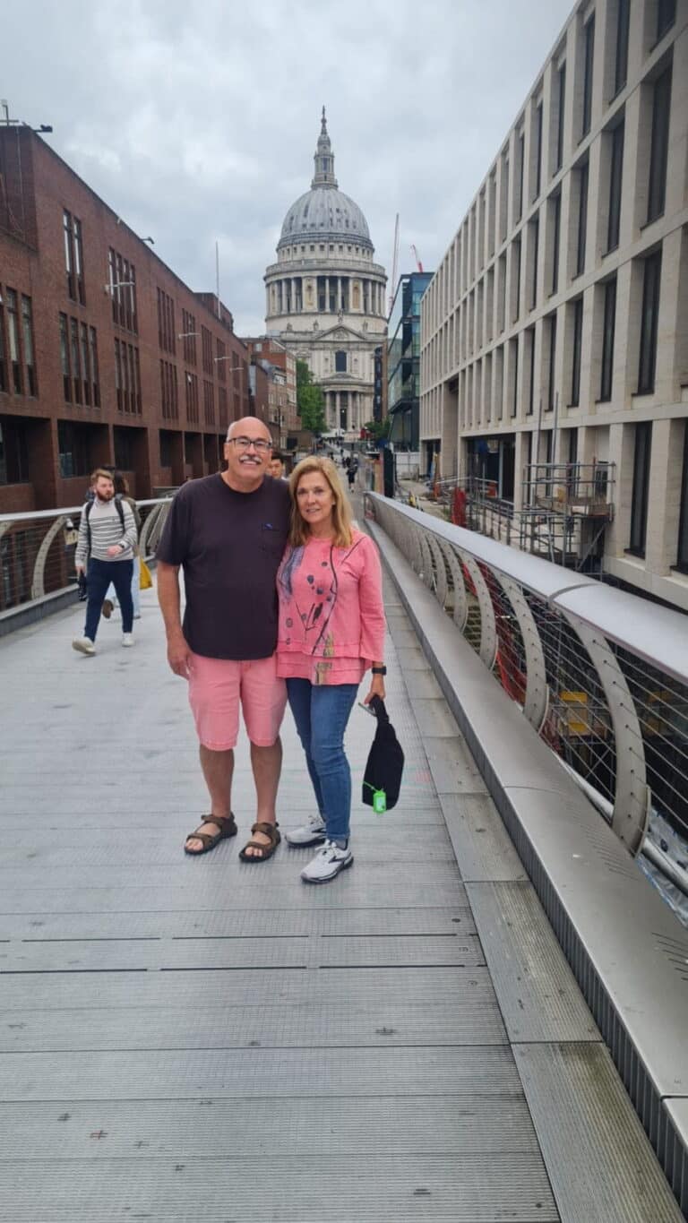 Tourists enjoying a London Sightseeing Tour on Millennium Bridge with St. Paul's Cathedral in the background.