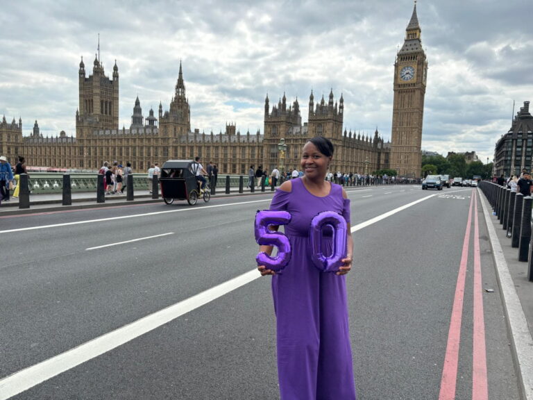 Woman celebrating a milestone on a London Top Sights Tour with the Houses of Parliament and Big Ben in the background.