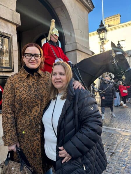 Two tourists smile in front of a mounted Household Cavalry soldier, highlighting a memorable moment from London Top Sights Tours.