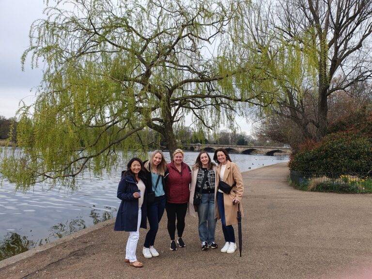 Group of friends on a Popular London Tours sightseeing experience near a scenic lake and bridge in London