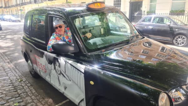 Best way to sightsee in London with professional black taxi cab tour guide in colorful shirt and sunglasses
