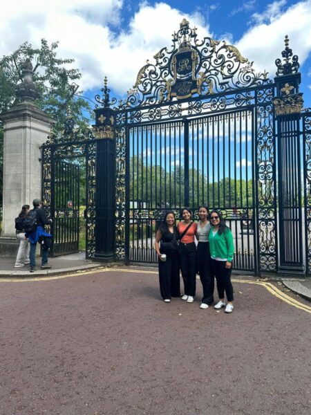 Visitors enjoying one of the Best Trips in London with London Sightseeing Taxi Tours, posing in front of ornate royal gates