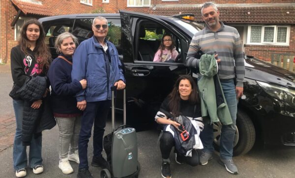 Group of visitors preparing for a Black Taxi Christmas Lights Tour in London with wheelchair-accessible vehicle and portable oxygen equipment