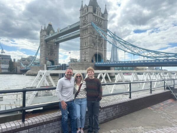 Tourists posing in front of iconic Tower Bridge during their London Trip Tickets experience with London Sightseeing Taxi Tours