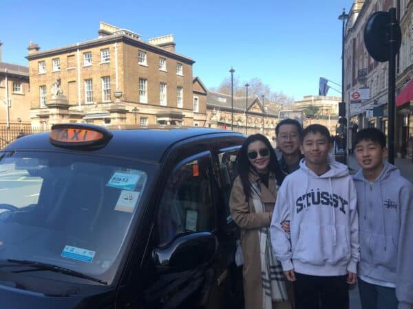 Group enjoying a Walking Tour Of London Sights with a classic London taxi in the city center