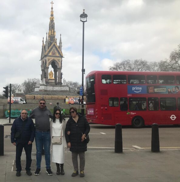Group of tourists enjoying iconic sights in London with London Sightseeing Taxi Tours, featuring the Albert Memorial and a red double-decker bus