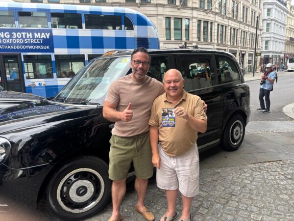 Tourists enjoying Special Places To Visit In London with a black taxi and London bus in the background