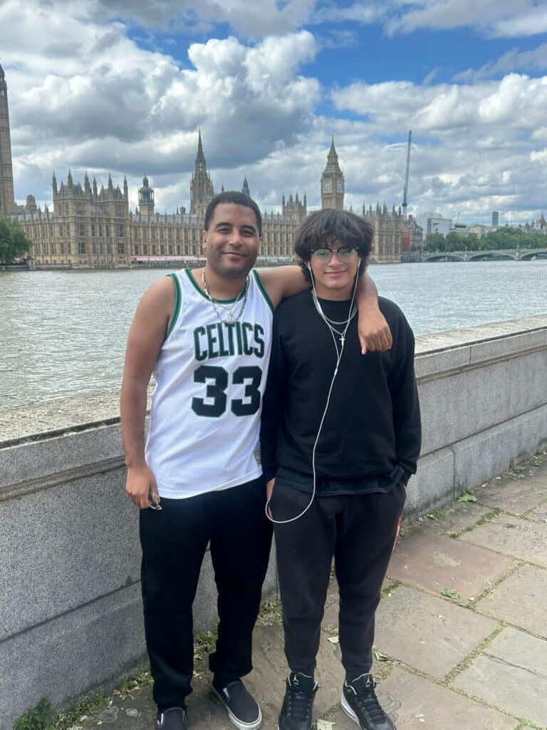 Two tourists on Thames riverside with London landmarks during Tours To London From Us