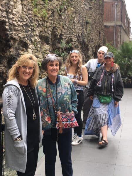 Group of tourists enjoying a Perfect London Itinerary with a London Sightseeing Taxi Tour near historic stone walls in London