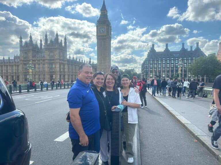 Group enjoying London City Lights Tour by taxi on Westminster Bridge in front of Big Ben and Houses of Parliament