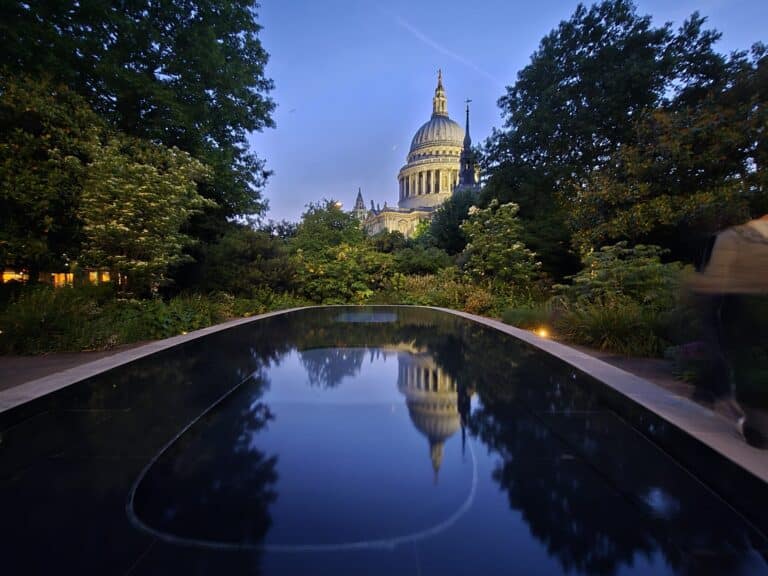 Amazing Places To Go In London - St Paul's Cathedral reflected in a serene pool surrounded by greenery during dusk