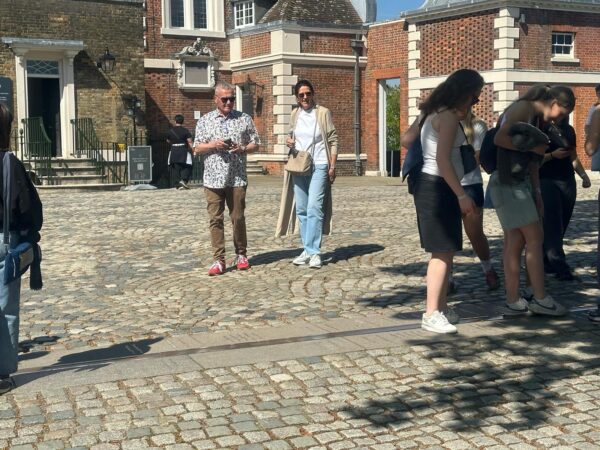Group of tourists enjoying sightseeing bus London tour near historic brick buildings and cobblestone streets