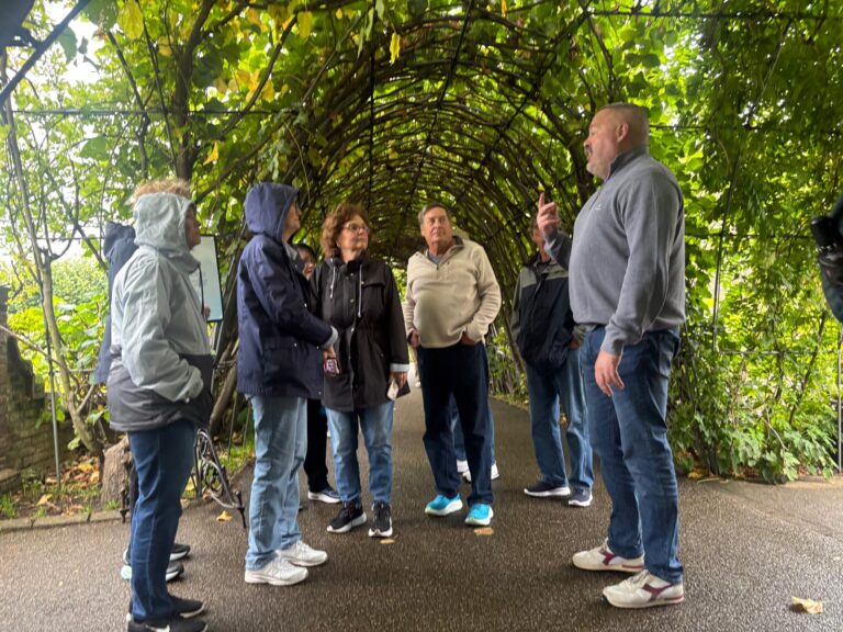 Group of tourists walking under vine-covered archway during Cotswolds tours from London with private sightseeing taxi service