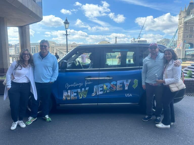 tours of stonehenge from london - group of tourists posing with wheelchair-accessible taxi tour van near Tower Bridge before embarking on day trip to Stonehenge