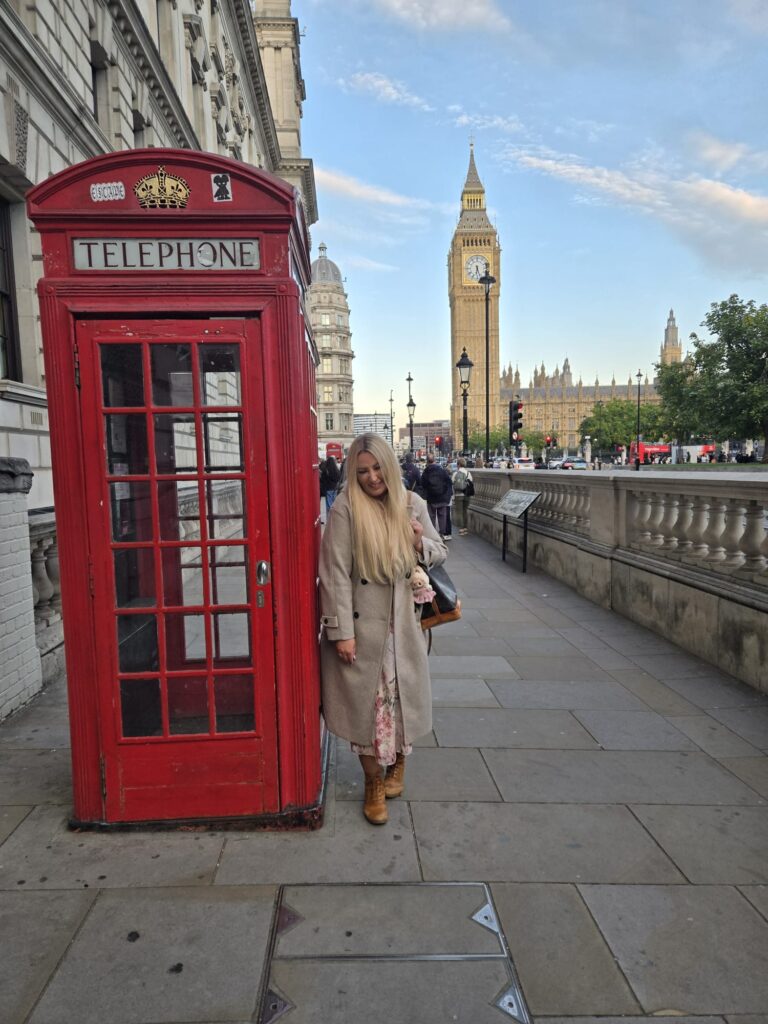 Visitor enjoying premium tours UK in London beside classic red telephone booth and Big Ben during sightseeing taxi tour