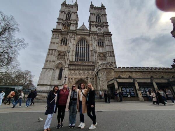Friends on a Harry Potter walking tour in London, posing in front of iconic Westminster Abbey with London Sightseeing Taxi Tours