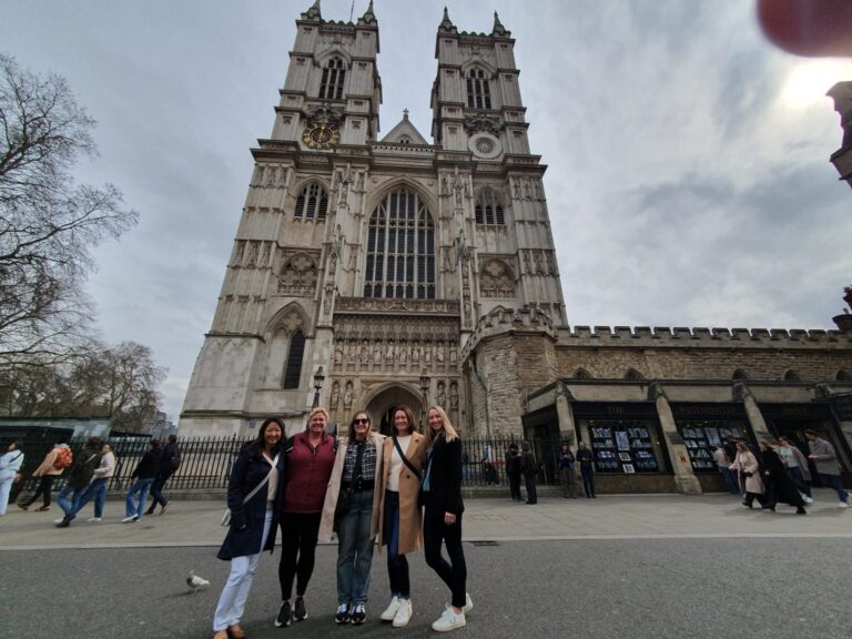 Friends on a Harry Potter walking tour in London, posing in front of iconic Westminster Abbey with London Sightseeing Taxi Tours