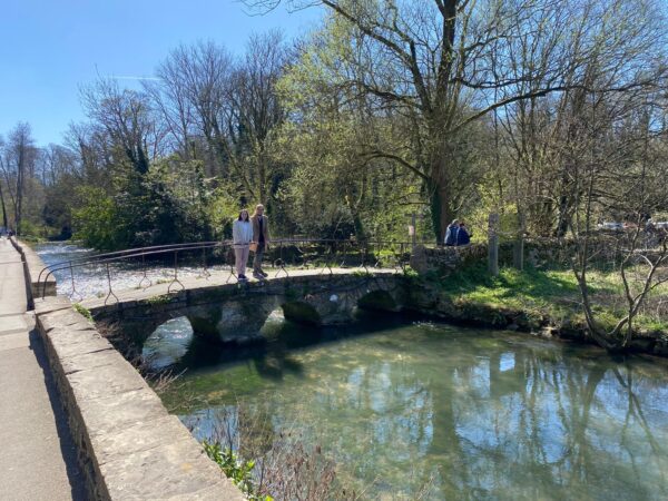 London in a day adventure with London Sightseeing Taxi Tours, visitors enjoying a picturesque stone bridge over a serene stream