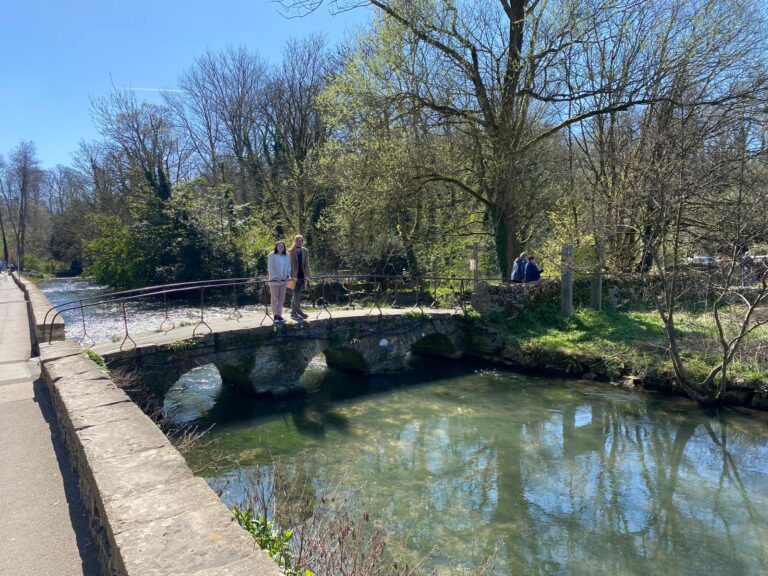 London in a day adventure with London Sightseeing Taxi Tours, visitors enjoying a picturesque stone bridge over a serene stream