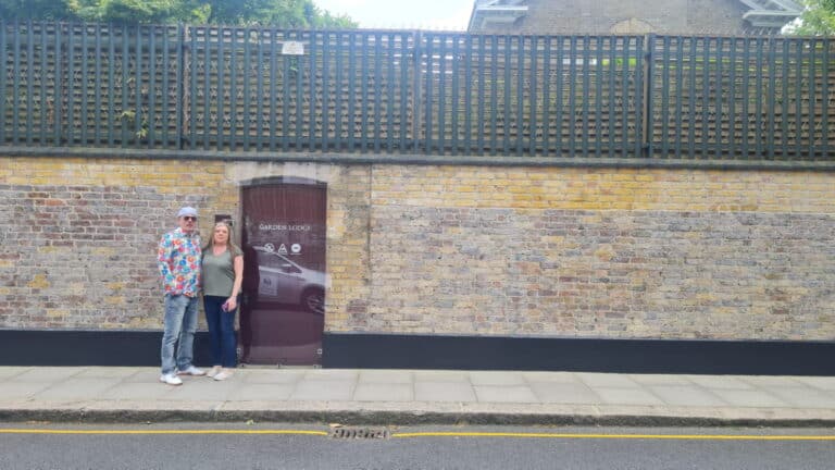 Places Not To Miss In London: Two visitors standing by a historic London wall during a London Sightseeing Taxi Tour