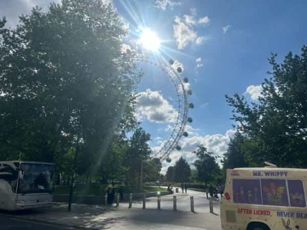 London The Most Famous Places - view of the London Eye, buses, and ice cream van near trees on a sightseeing taxi tour