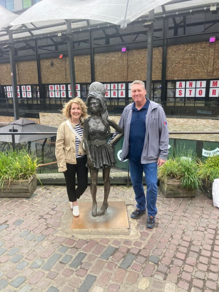 Two tourists from london day tours standing beside a bronze statue in Camden Market