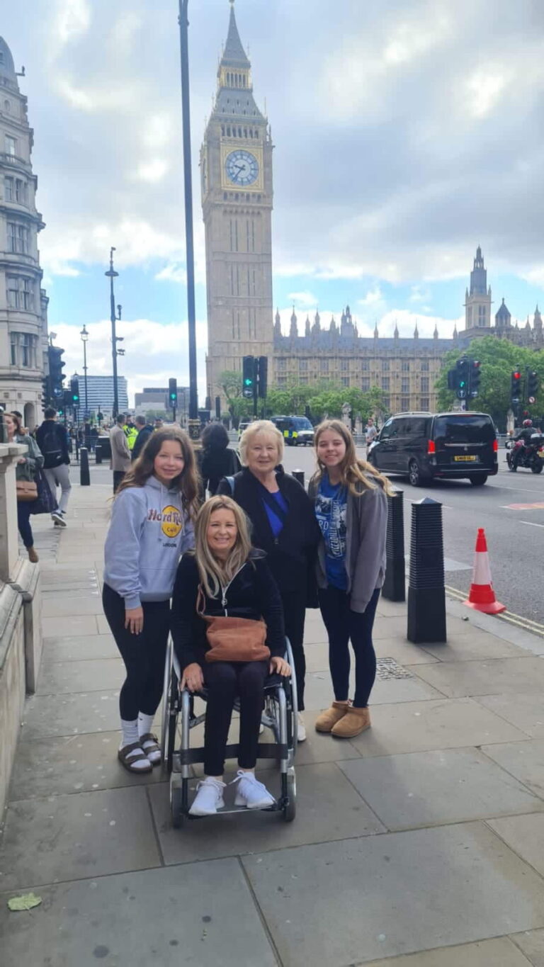 Group of visitors enjoying private day tours from London with London Sightseeing Taxi Tours, posing in front of Big Ben and Houses of Parliament, wheelchair accessible vehicle service