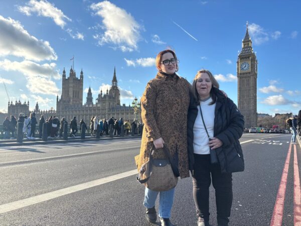 Visitors enjoying private tours in London, posing in front of Big Ben and Houses of Parliament on Westminster Bridge with London Sightseeing Taxi Tours