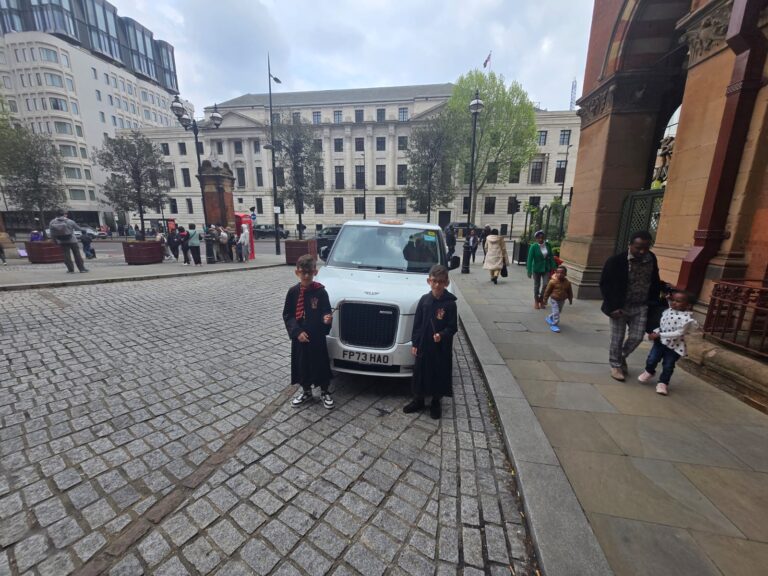 Children in Harry Potter costumes posing for london day trips tours with London Sightseeing Taxi Tours black cab outside historic London landmark