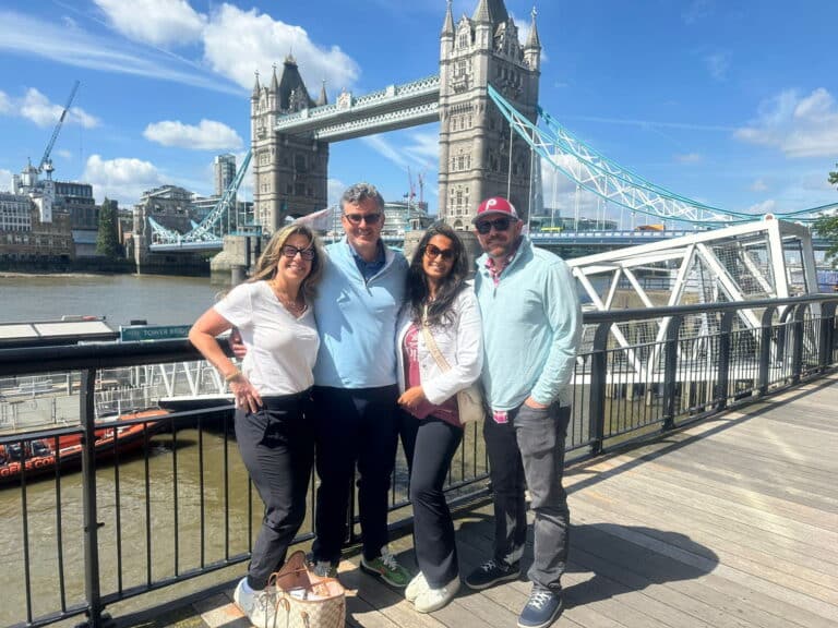 Group of tourists enjoying private Stonehenge tour from London with sightseeing at iconic Tower Bridge in summer weather